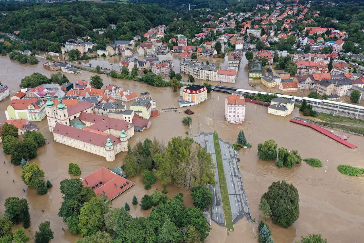 Coloured roofs of buildings and trees peaking through murky floodwaters.