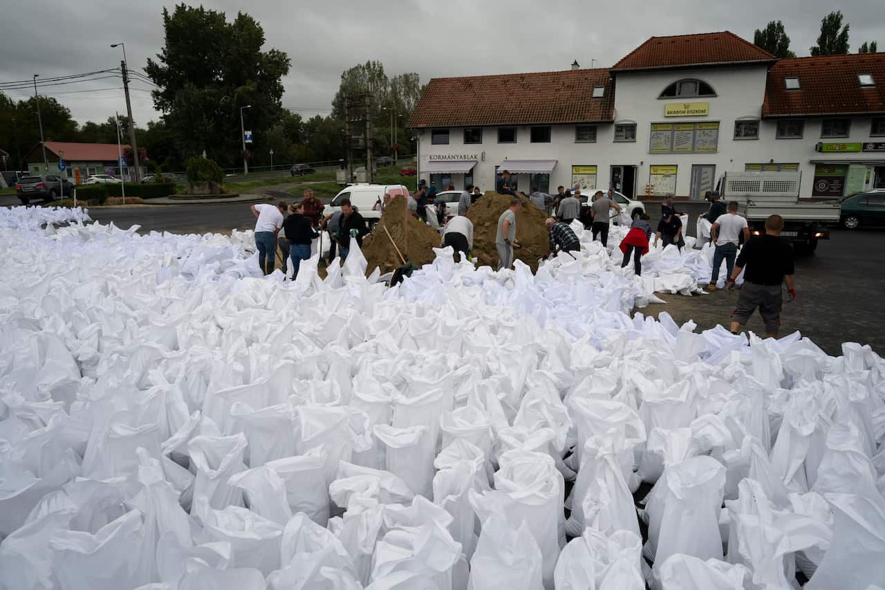 People place hundreds of white bags on the road outside a building.