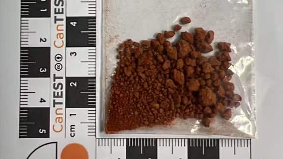 A brown powdered substance in a plastic bag on a measuring scale.