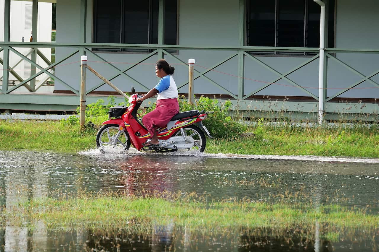 A woman rides a scooter through the water.