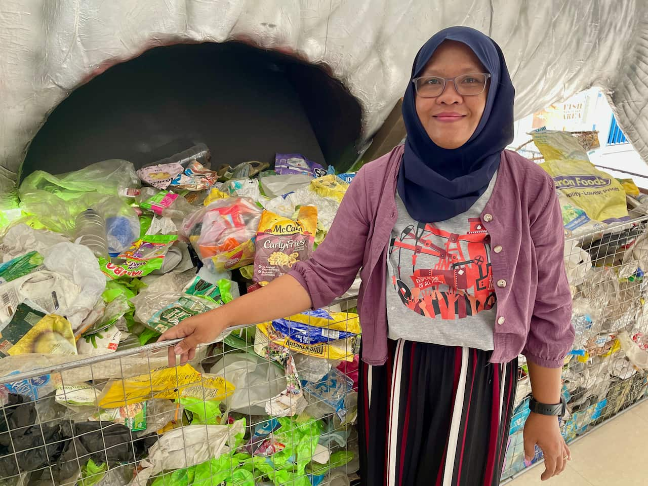 Daru Setyorini, an Indonesian woman who runs Ecoton Foundation, stands in front of piles of plastic rubbish.