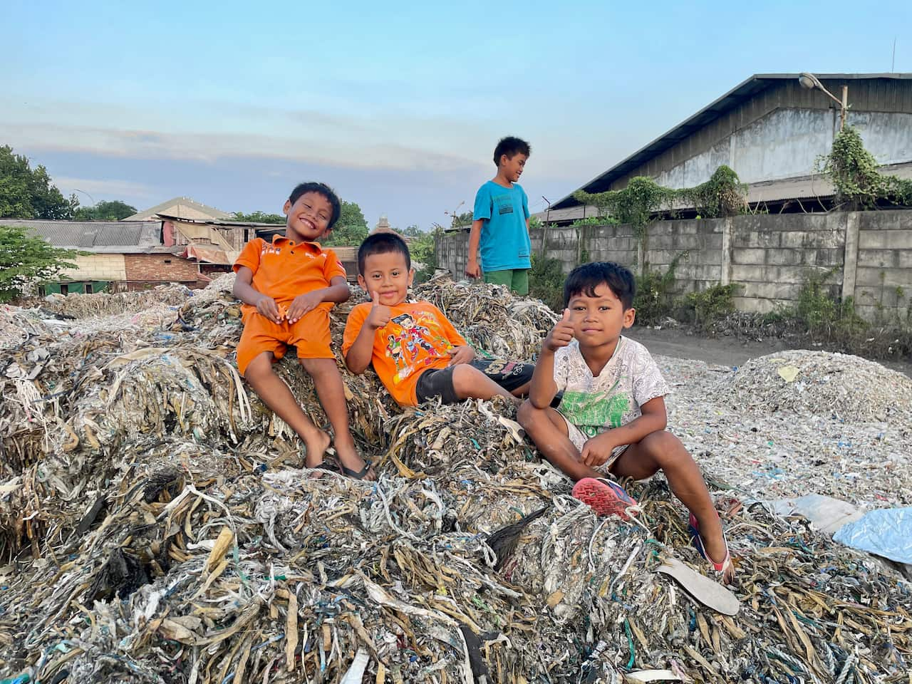 Three boys sitting on a pile of shredded waste pose for a photo