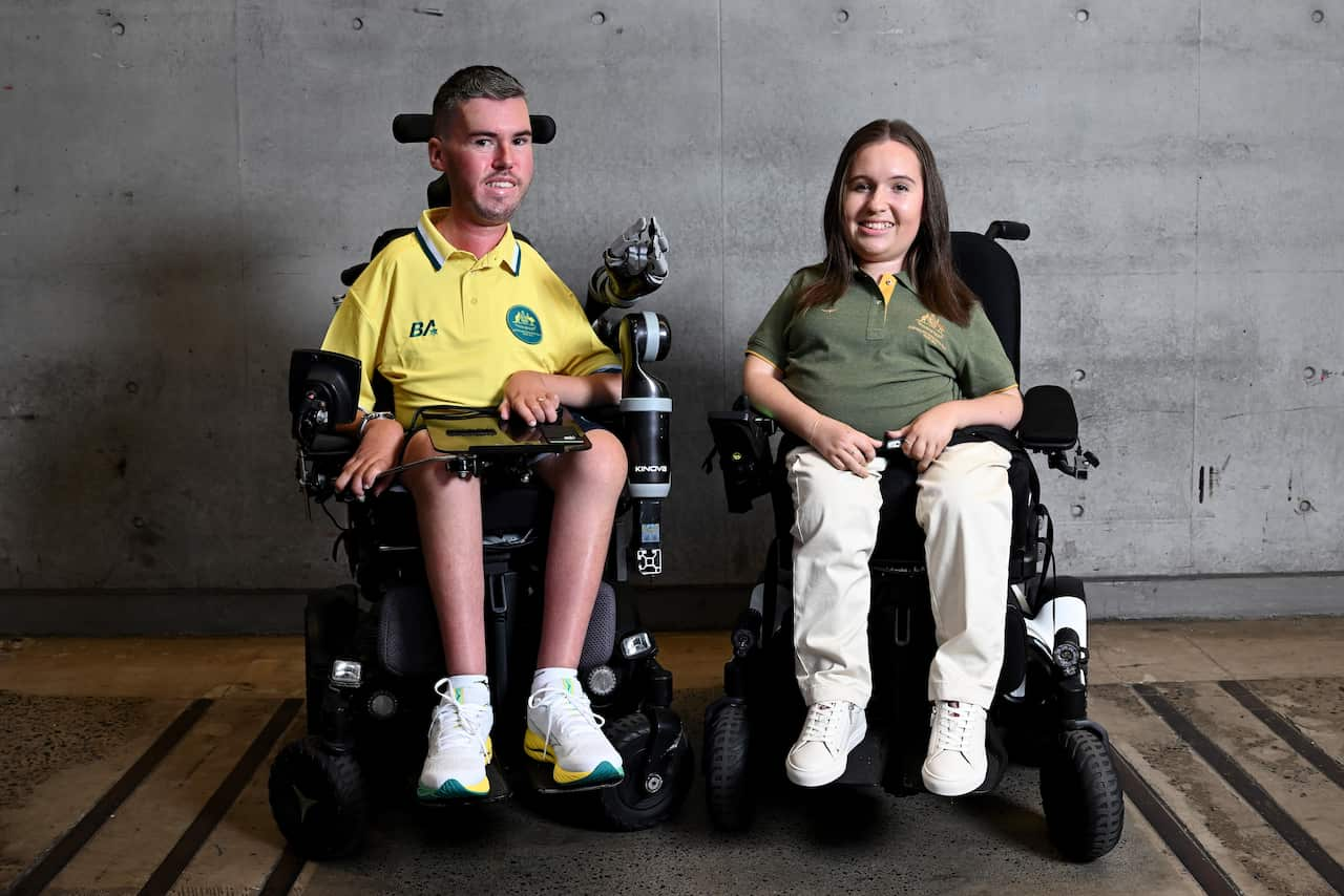 A man and a woman sit in wheelchairs wearing Australian Paralympic uniforms.