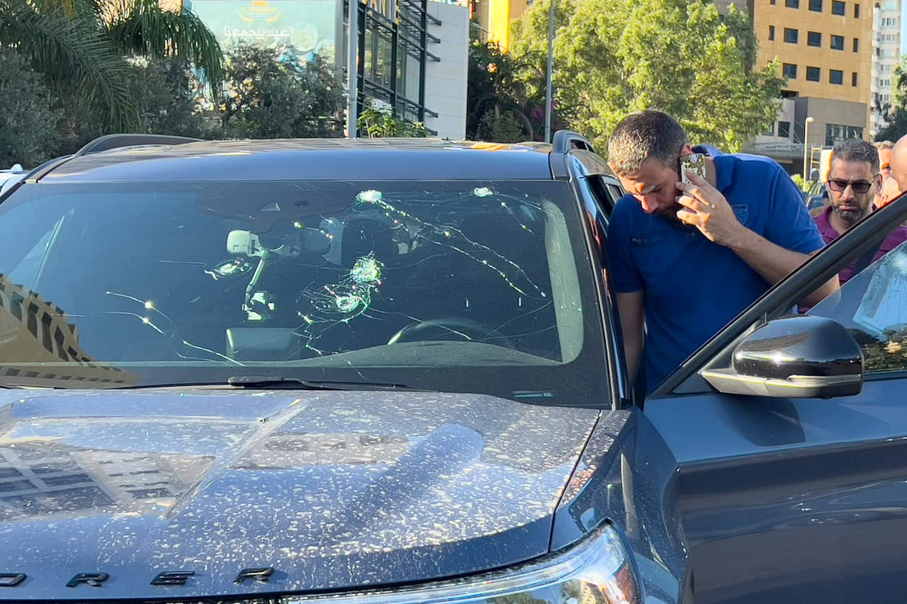 Police officer inspecting vehicle damaged by pager explosion