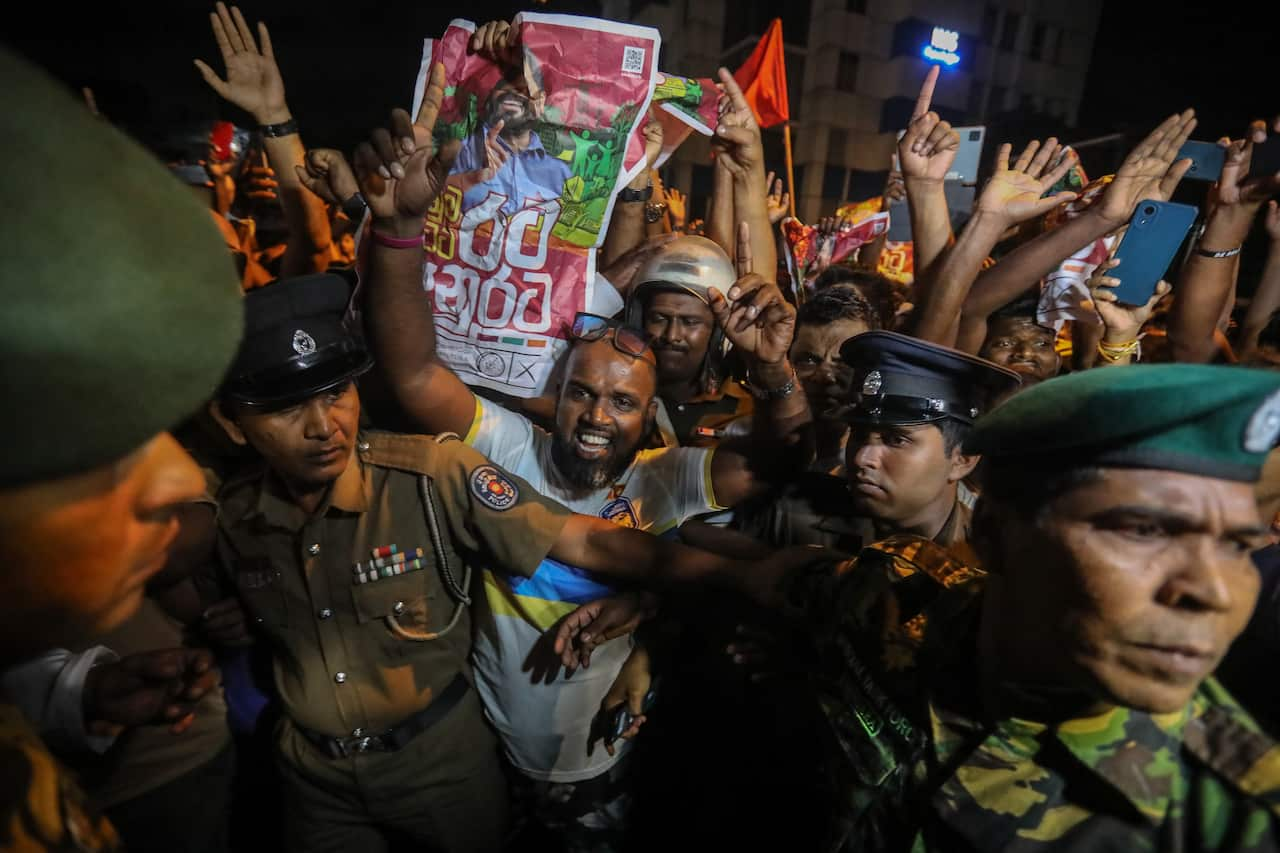 A jubilant crowd, some holding posters, gathered amid security officials.