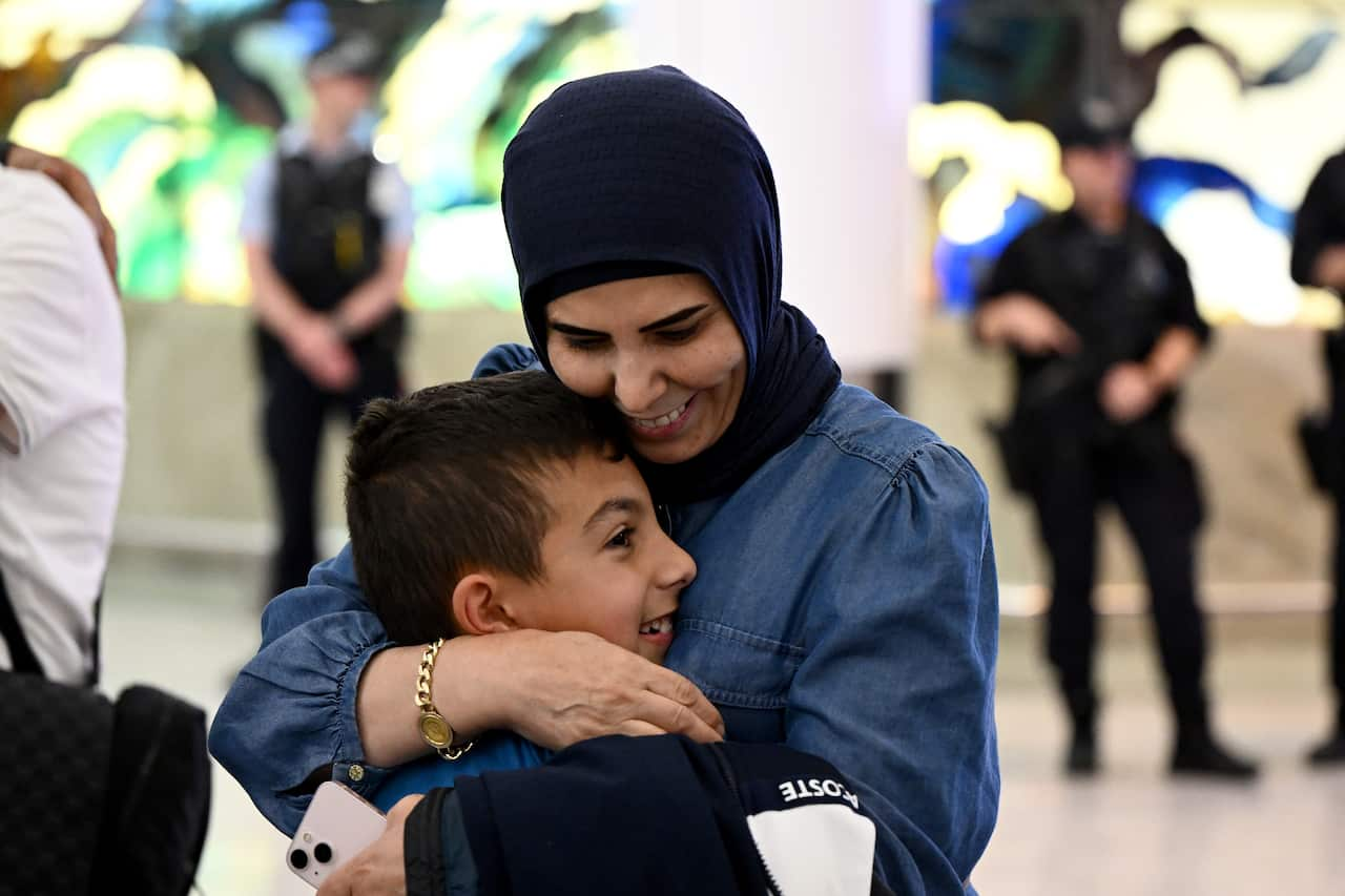 A woman and a young boy embrace and smile 