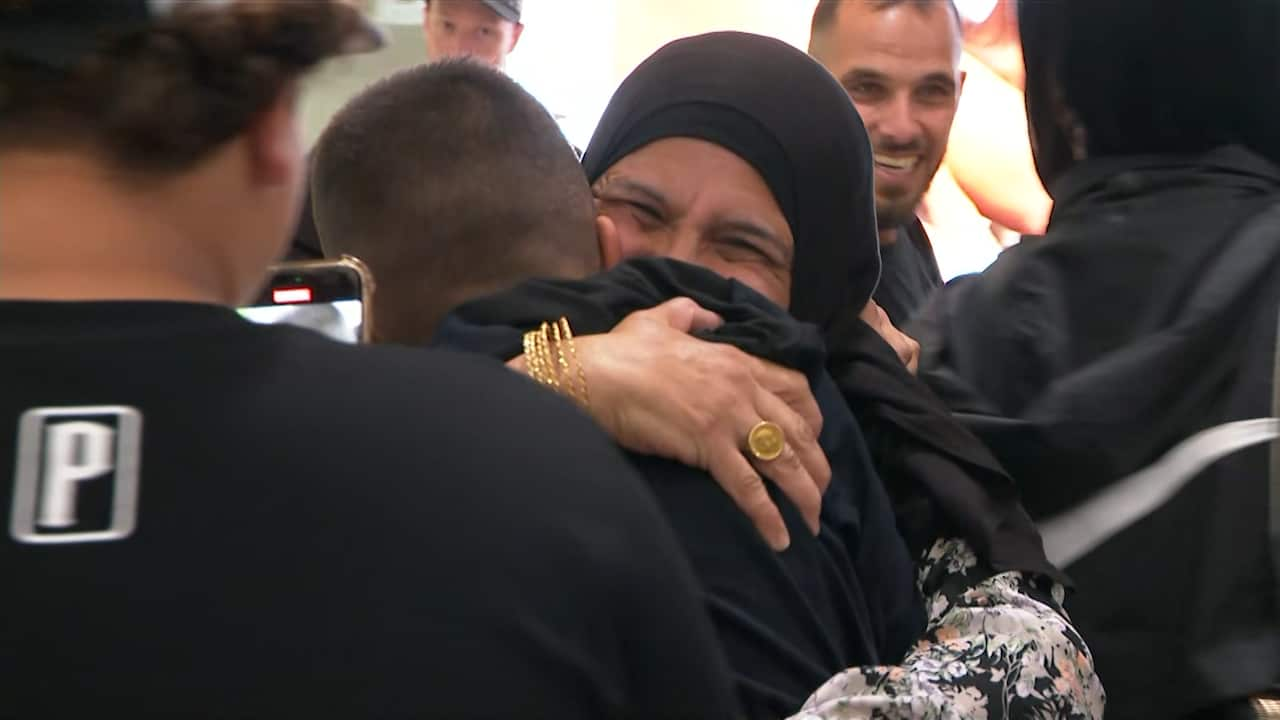 A man and a woman hug and smile at an airport.