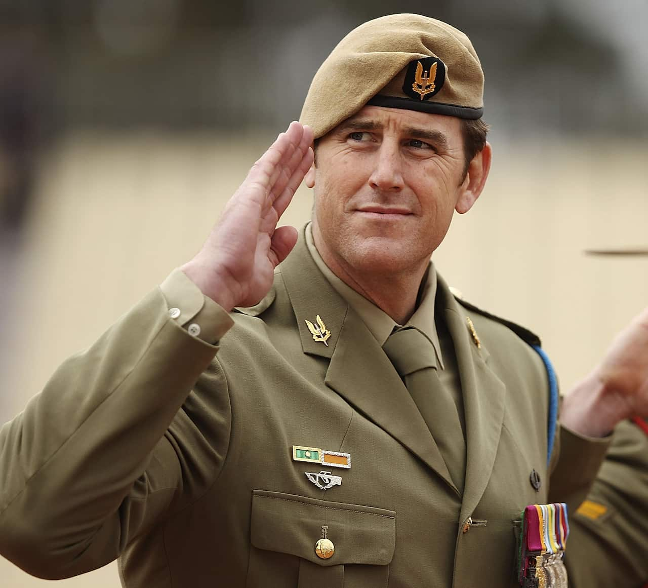 Ben Roberts-smith salutes wearing a green beret and army fatigues 