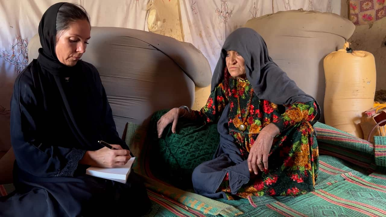 A woman in black takes notes from a woman in black headscarf 