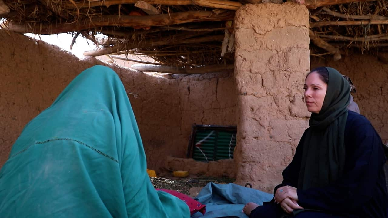 A woman covered in a blue robe talks to Michelle in a black shawl 