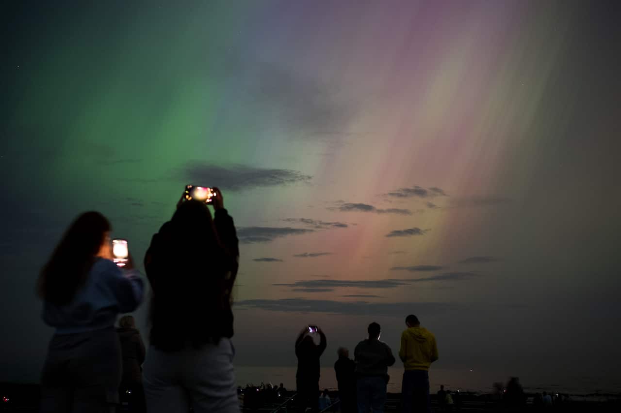 People using their phone cameras to take photos of northern lights.