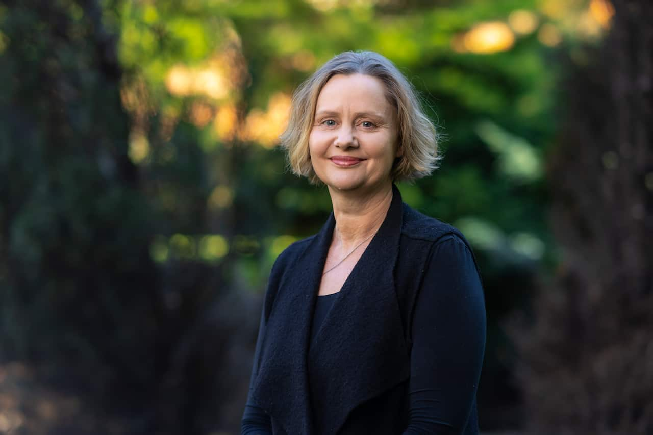 A woman with short blonde hair wearing a navy jacket 