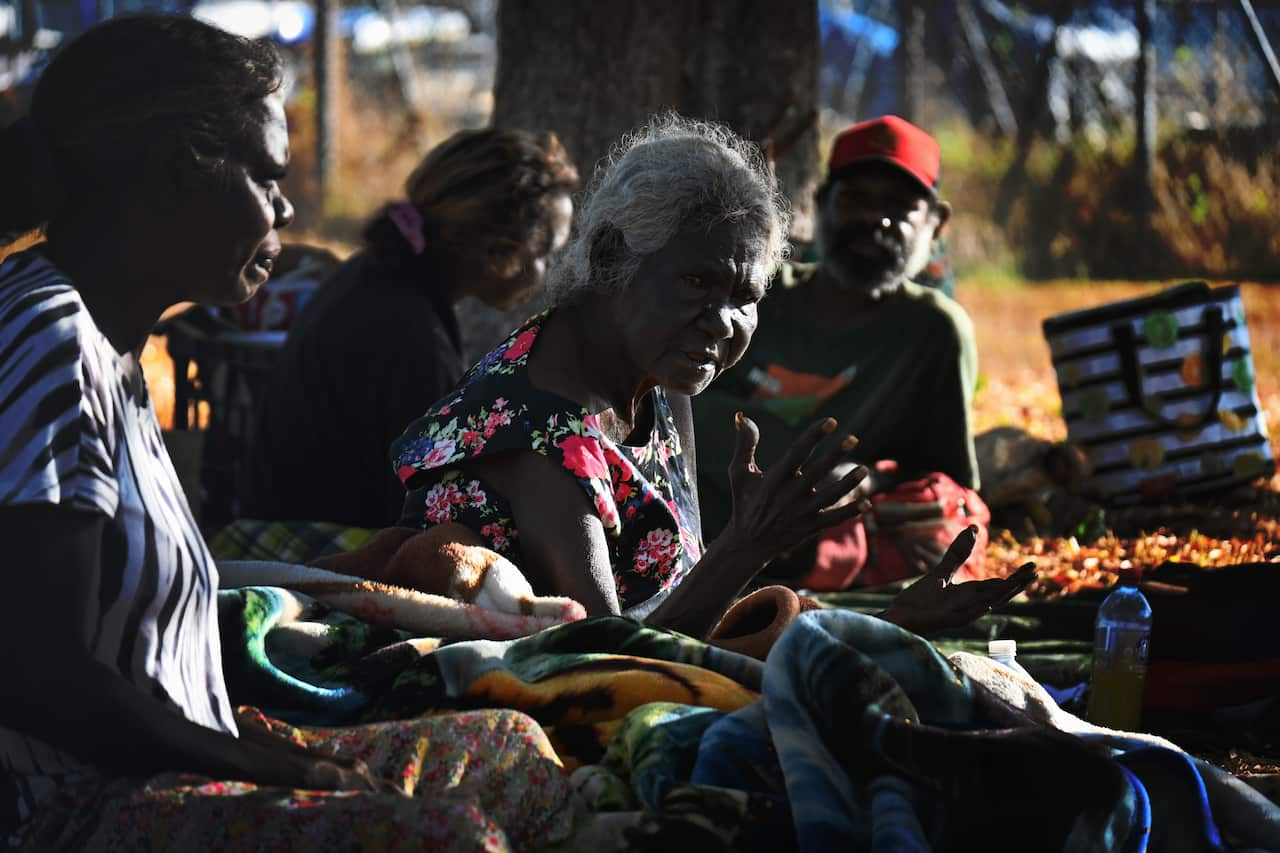 Jane Alimankinni sits with family at her beach-side camp in Darwin