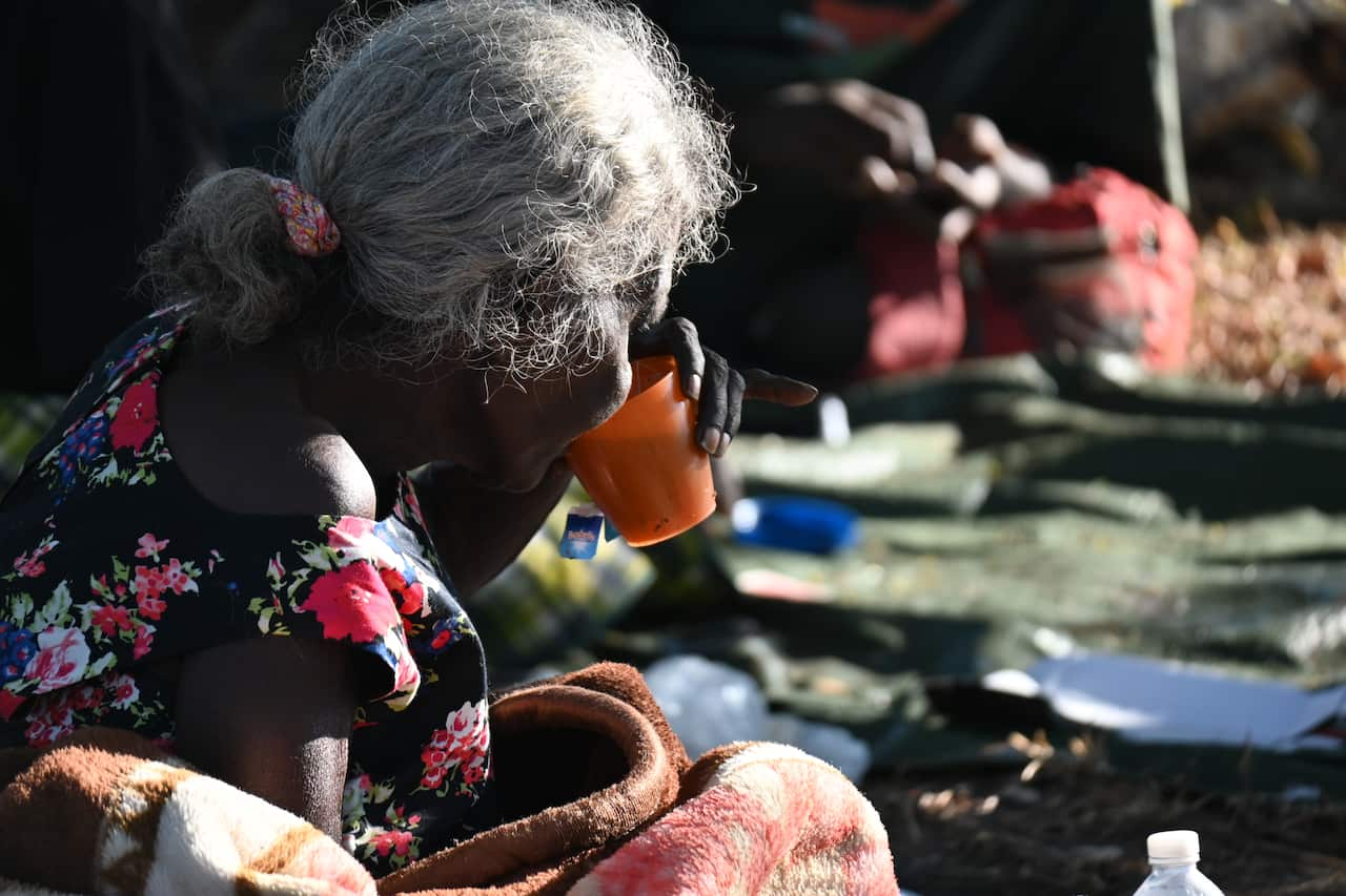 Jane Alimankinni drinks tea at her camp near a Darwin beach