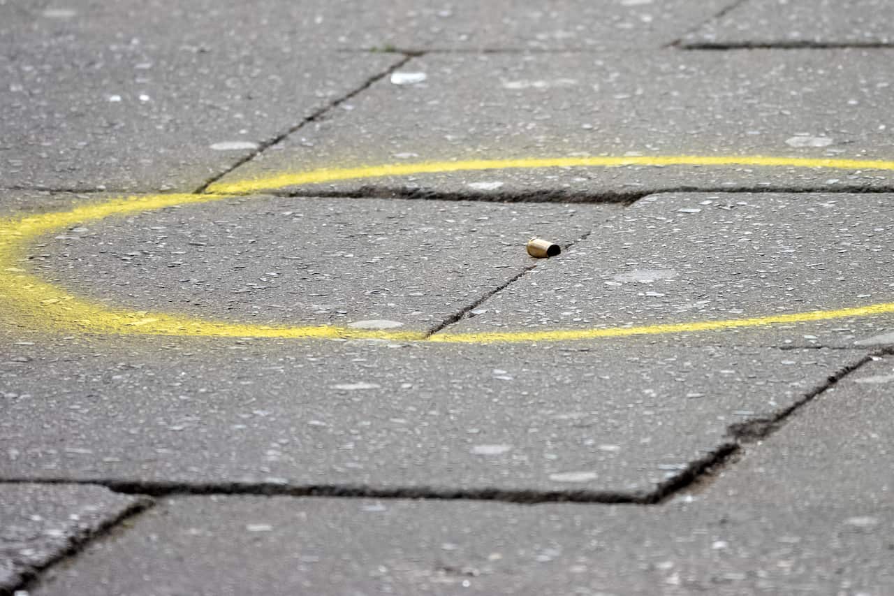 Yellow chalk surrounds a bullet casing on the ground.