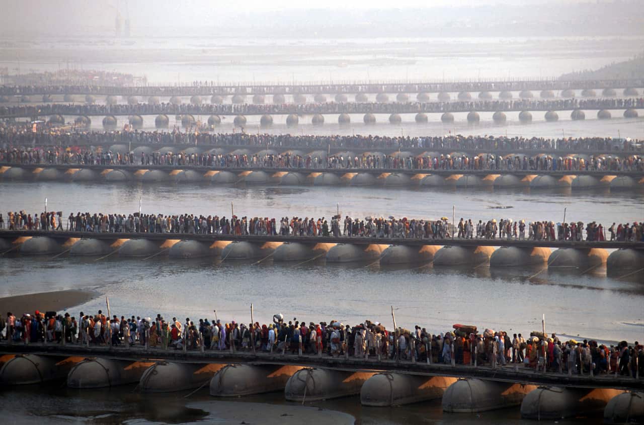 A huge amount of people crossing several bridges over water at low tide.