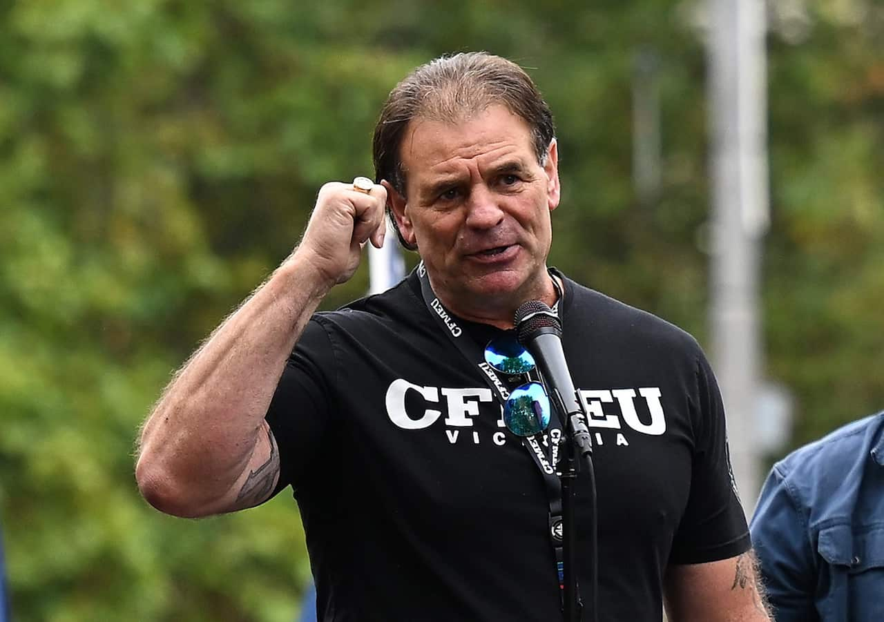 John Setka wearing a shirt that says "CFMEU Victoria" speaking into a microphone.