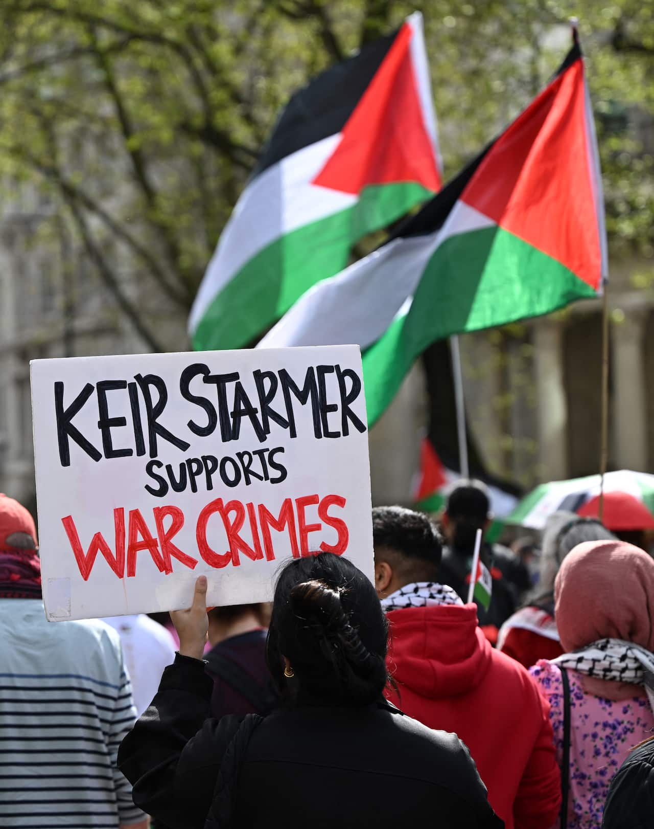 A pro-Palestinian protestor in London holds a sign saying 'Keir Starmer Supports War Crimes'.