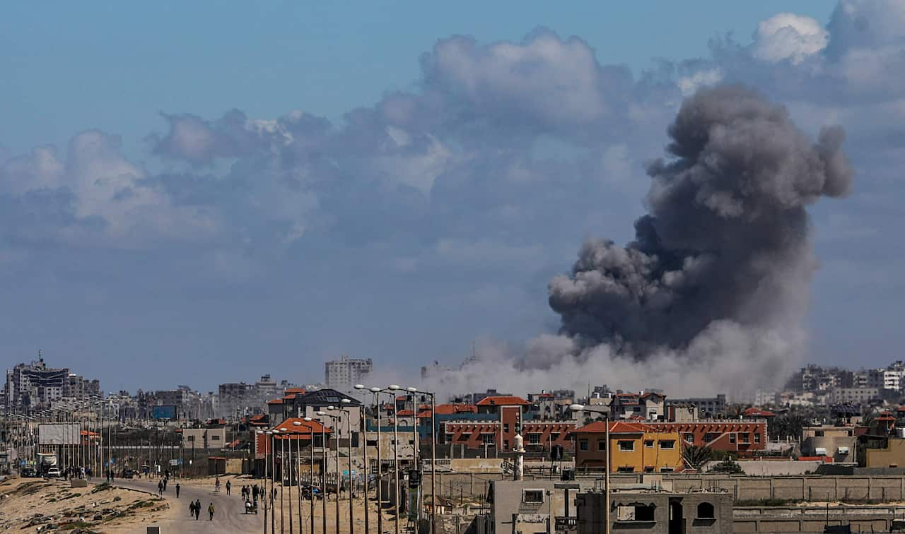 Smoke billowing in the background behind a row of buildings.