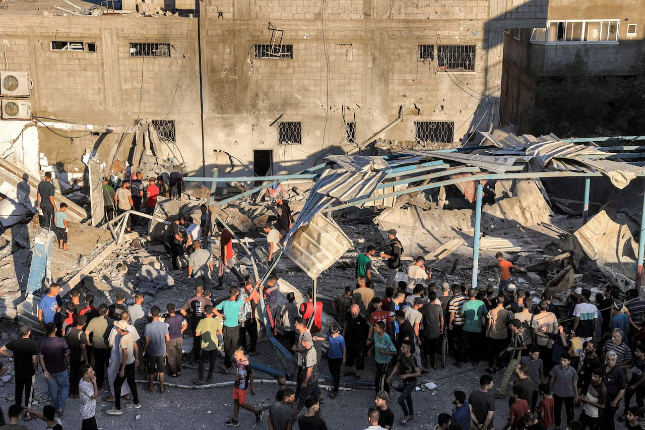 A large group of people inspecting the damage from a destroyed building.