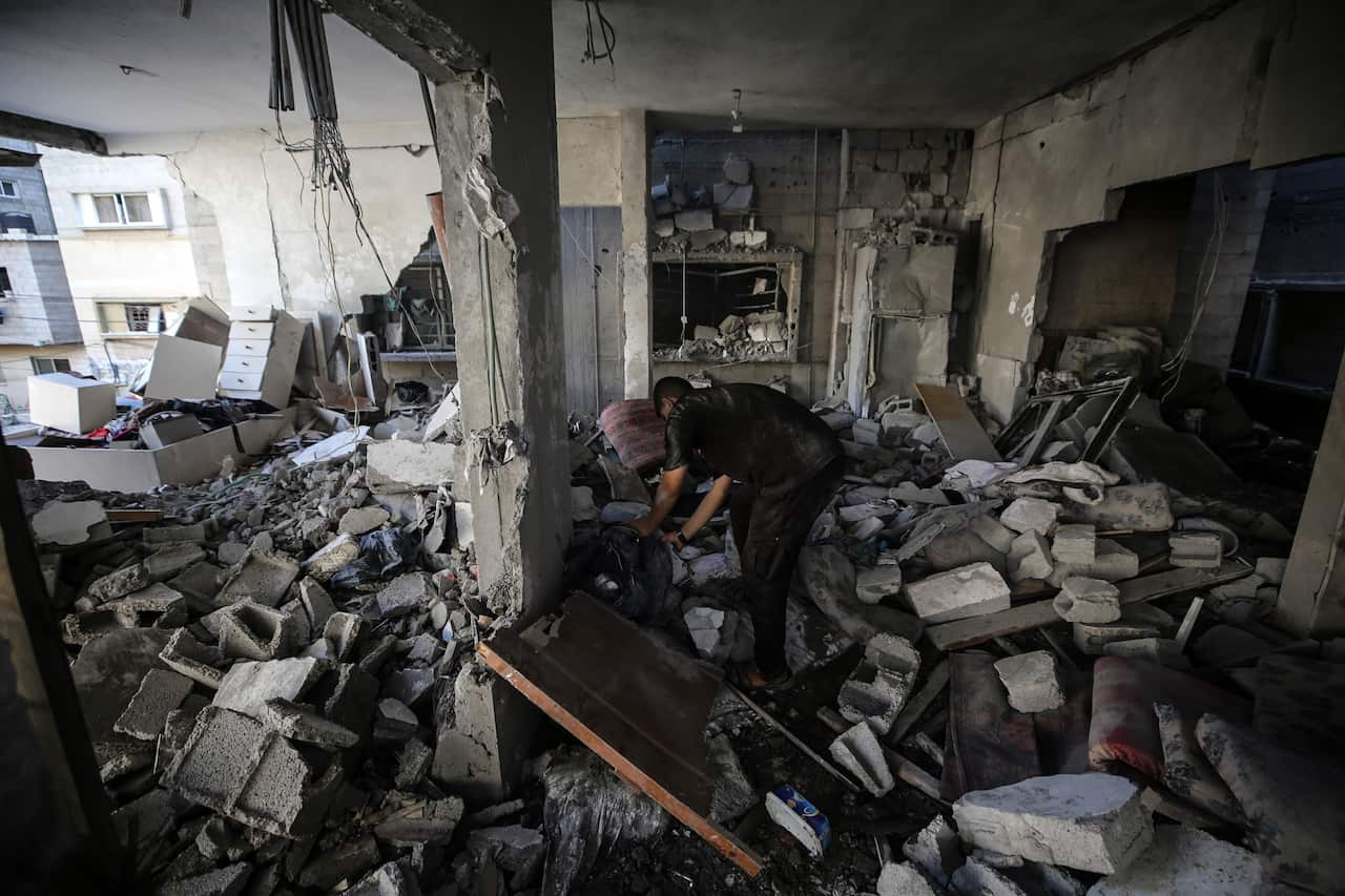 A person inspecting items in a destroyed building.