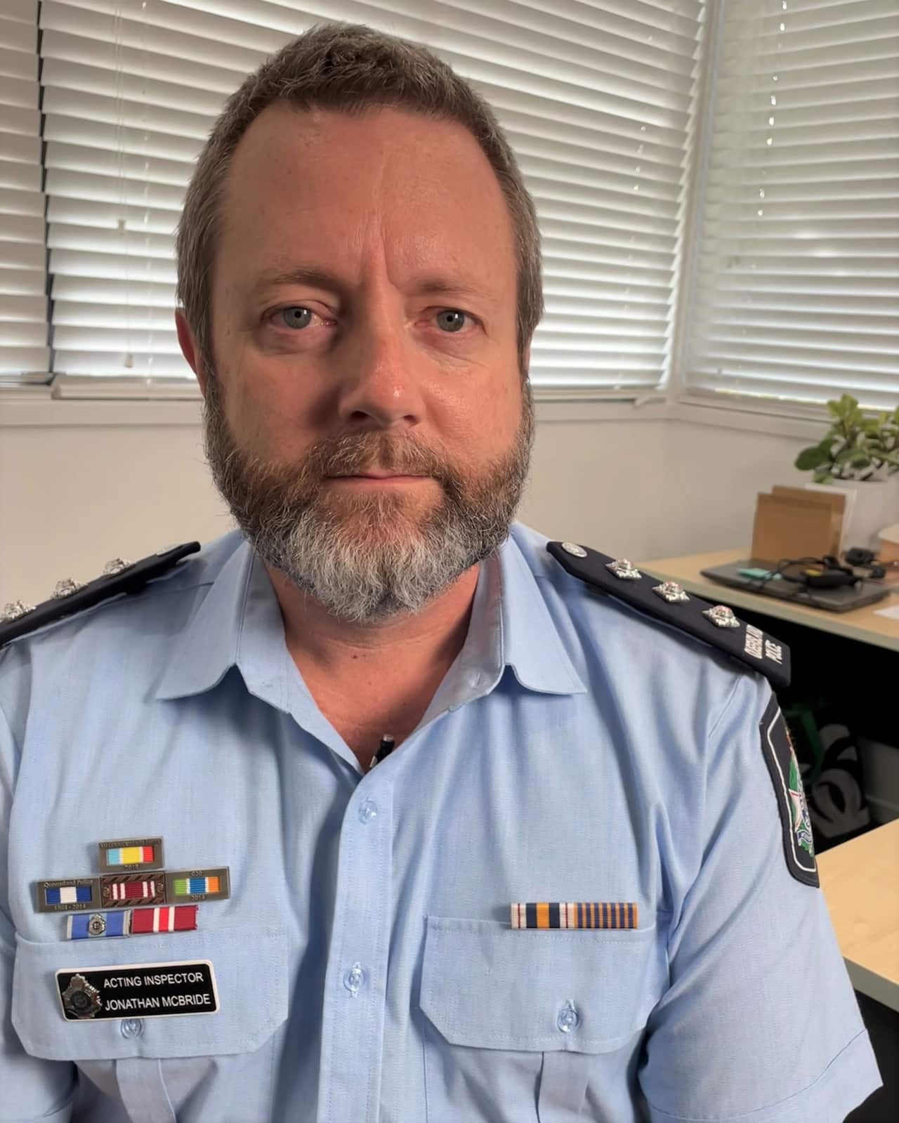 A police officer in uniform sits on a chair in an office.