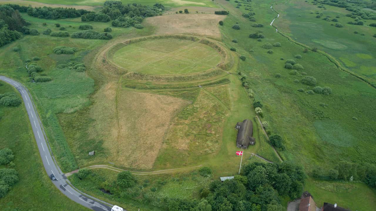 Aerial view of a large circular formation atop a grassy hill. 