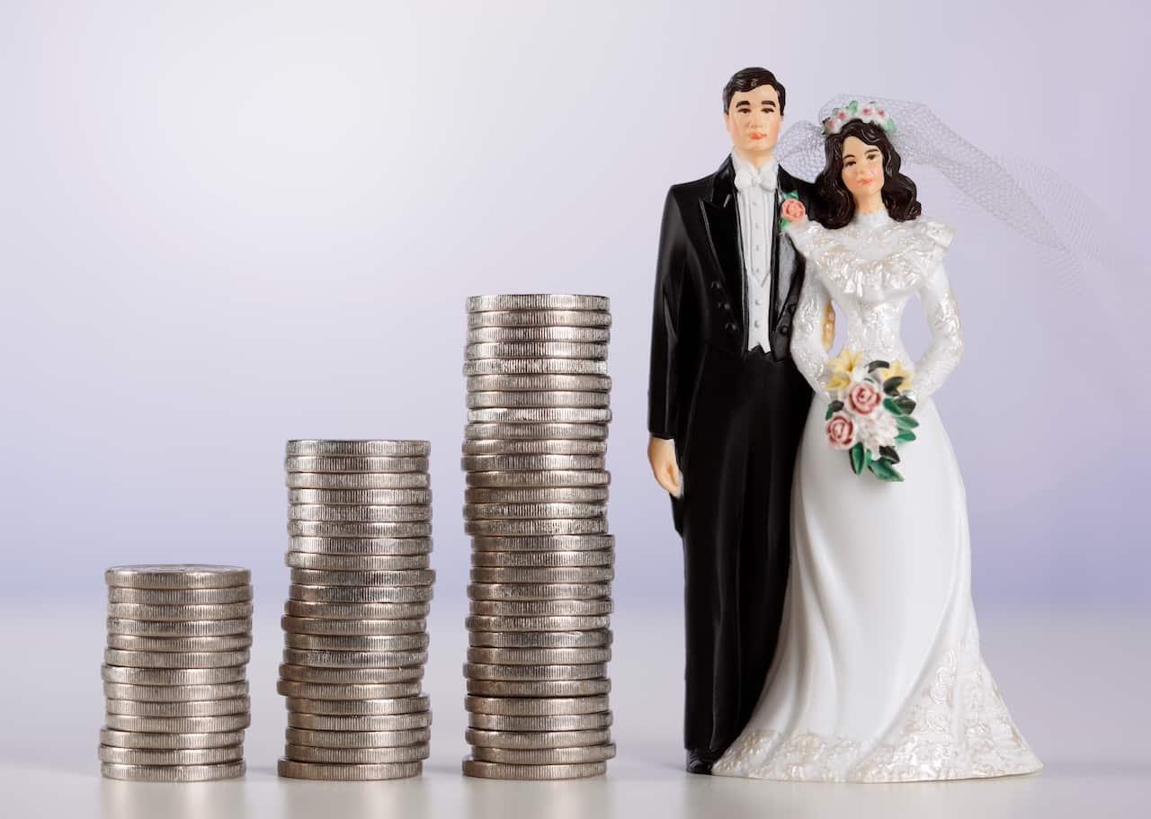 Piles of coins next to a figurine of a bride and a groom.