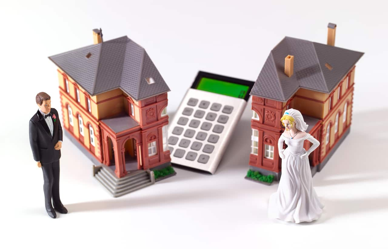 Small figurines of a man dressed in a suit, a woman in a wedding dress, two homes and a calculator 