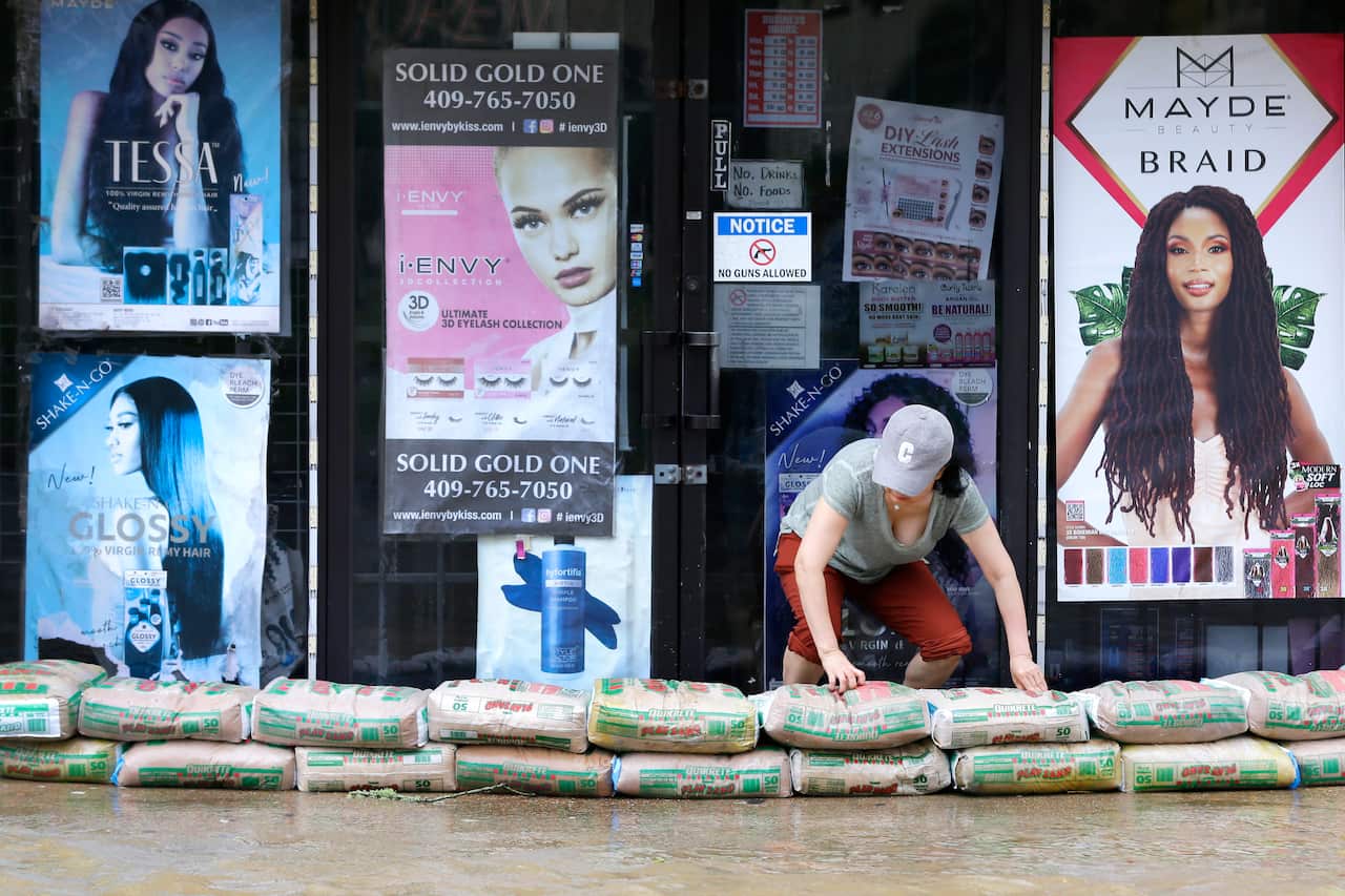 A shop owner piles sandbags around the entrance as street flooding approaches the building after Beryl has moved through in Galveston, Texas. 