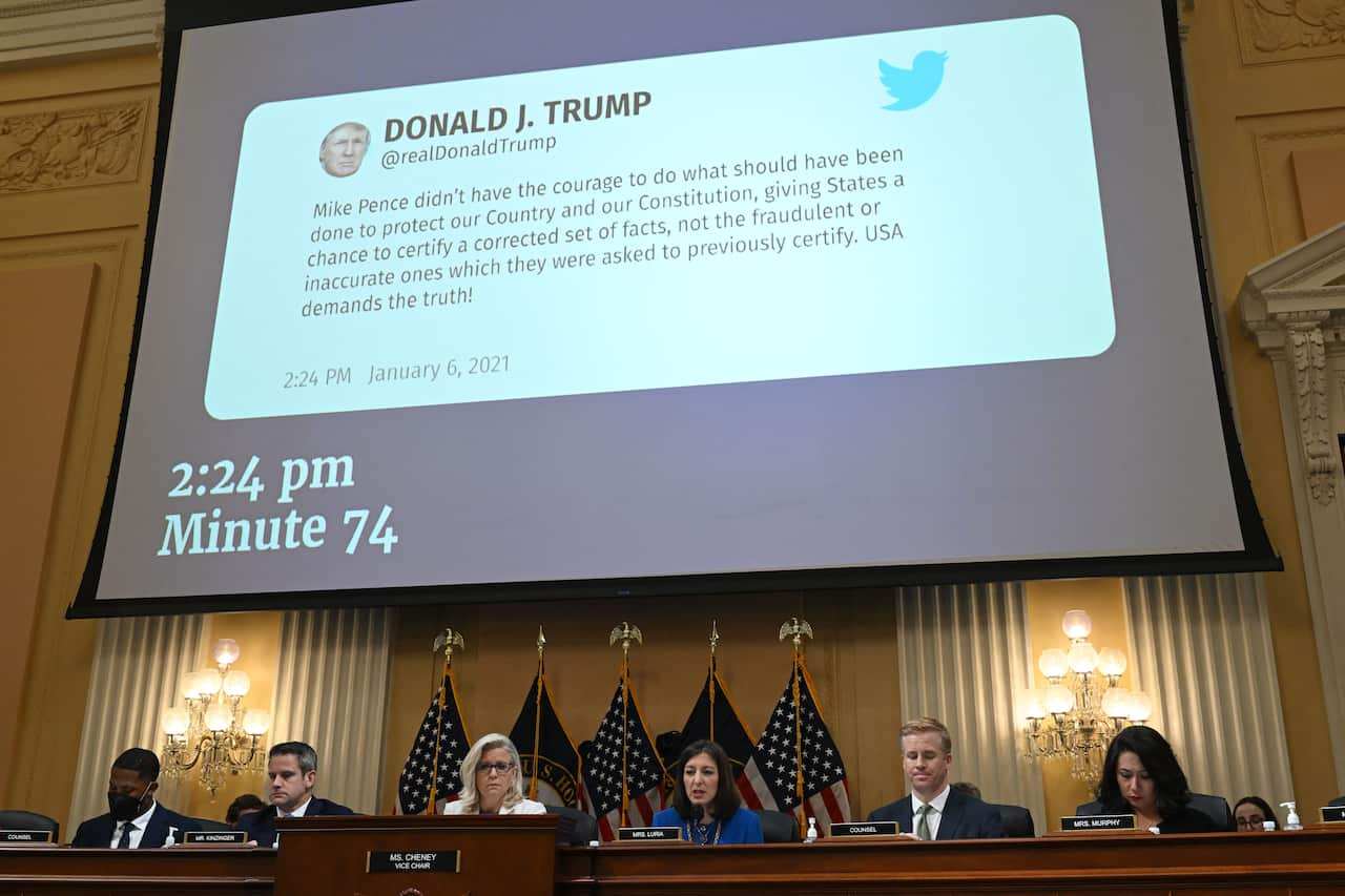 A tweet sent by Donald Trump on 6 January 2021 displayed on a large screen above members of a committee.