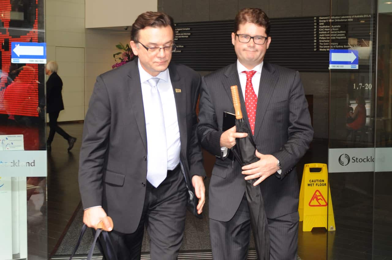 Two men dressed in suits walk out of a doorway