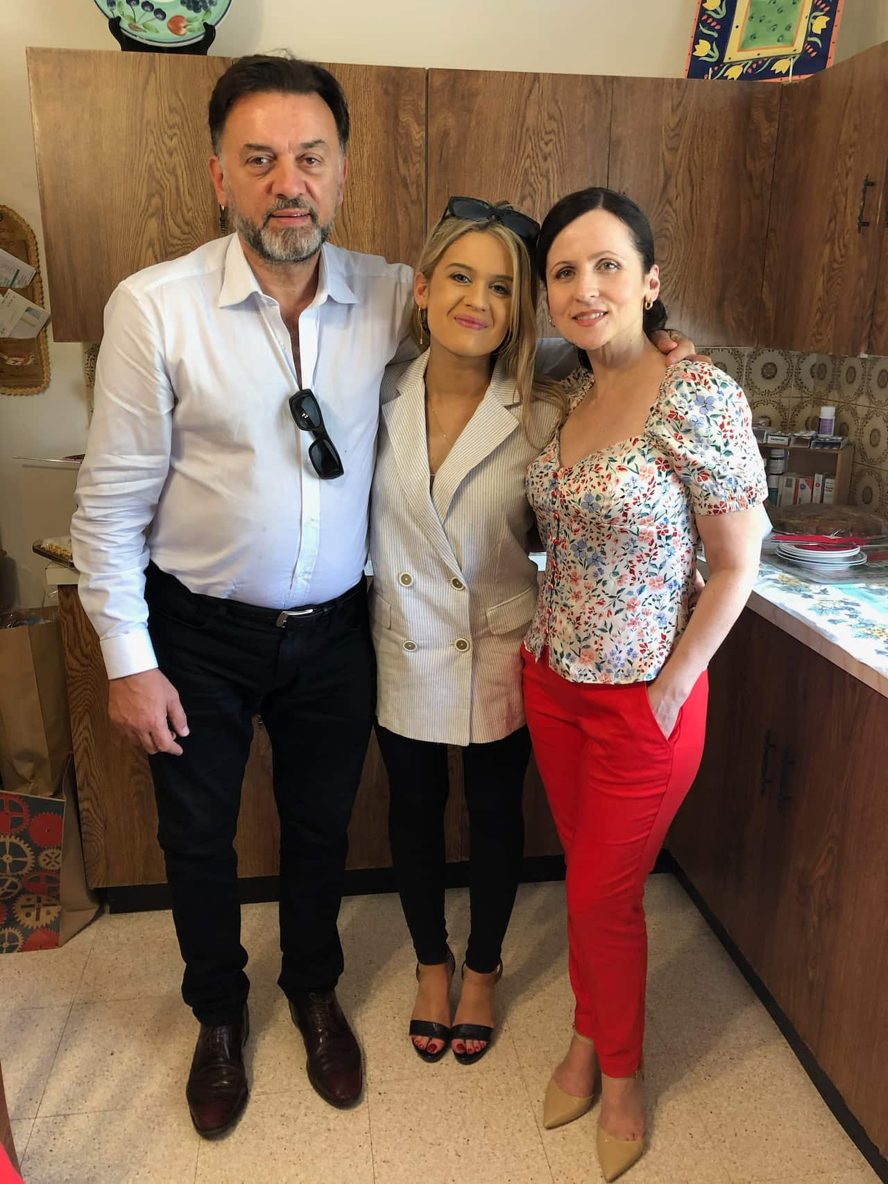 A man poses with his wife and daughter in a kitchen