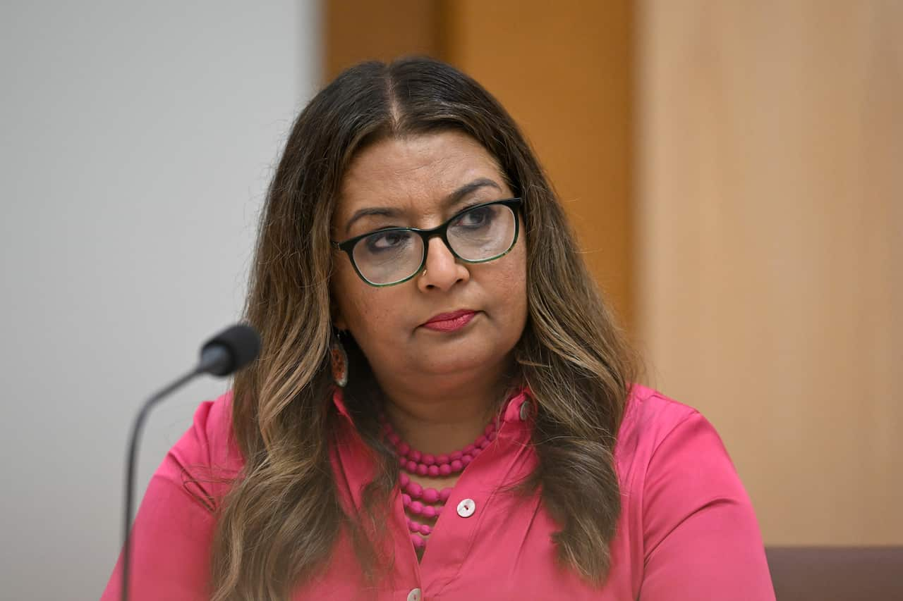 A woman listening while seated in front of a microphone.