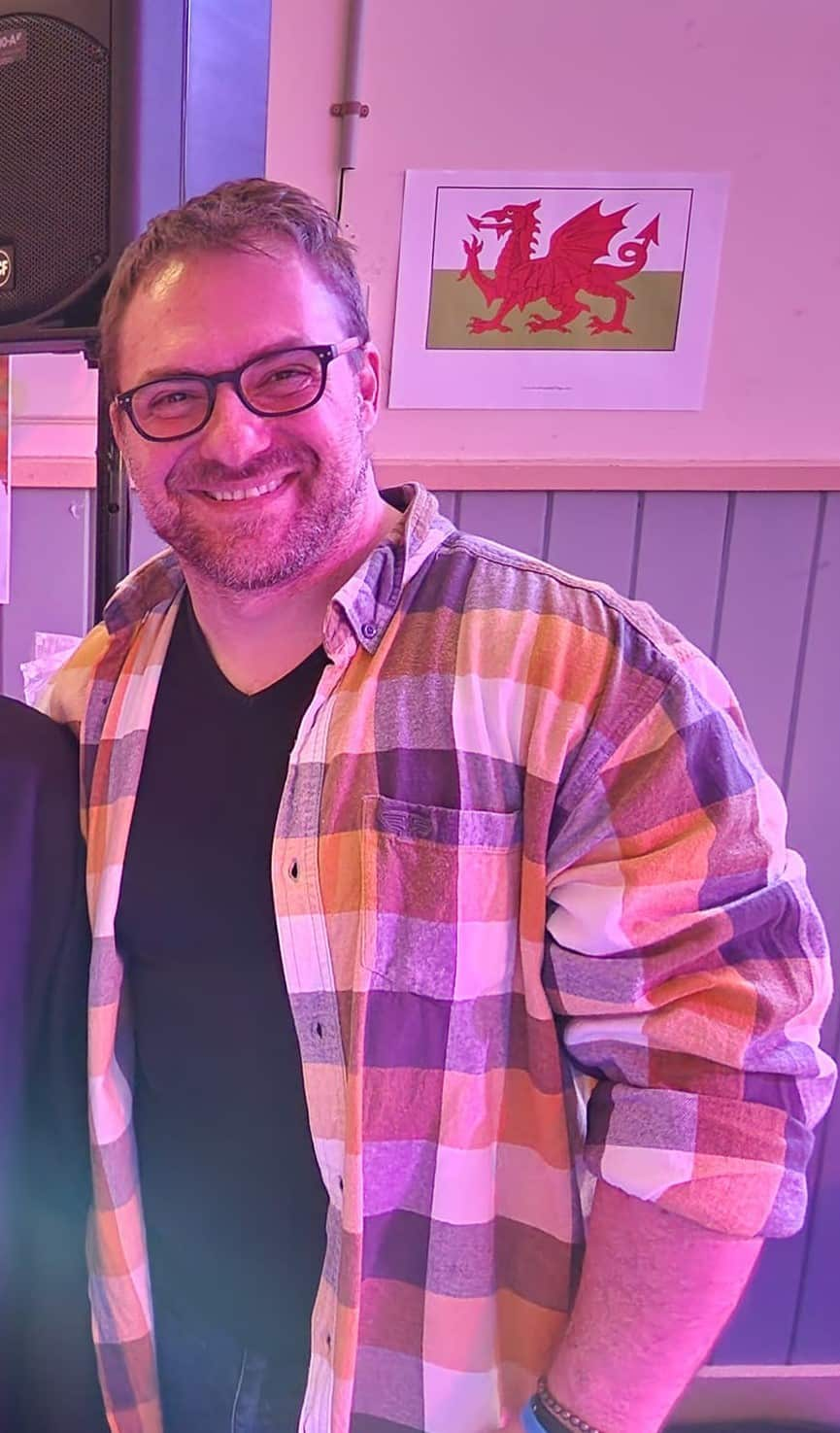 a man wearing a check shirt smiling