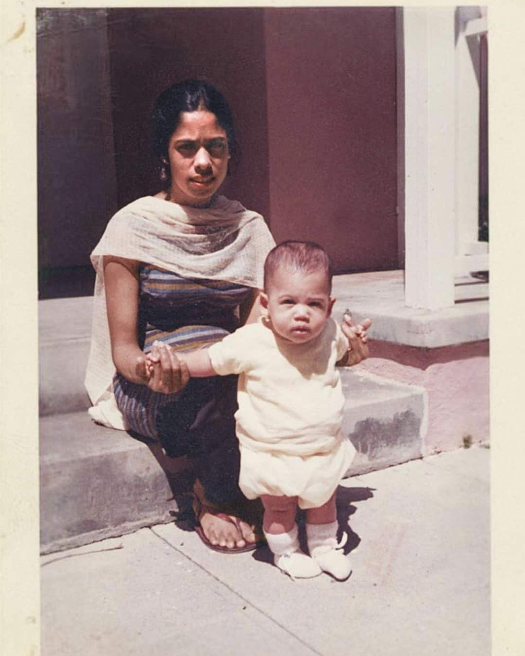 Kamala Harris as a young baby with her mother sitting on a step.