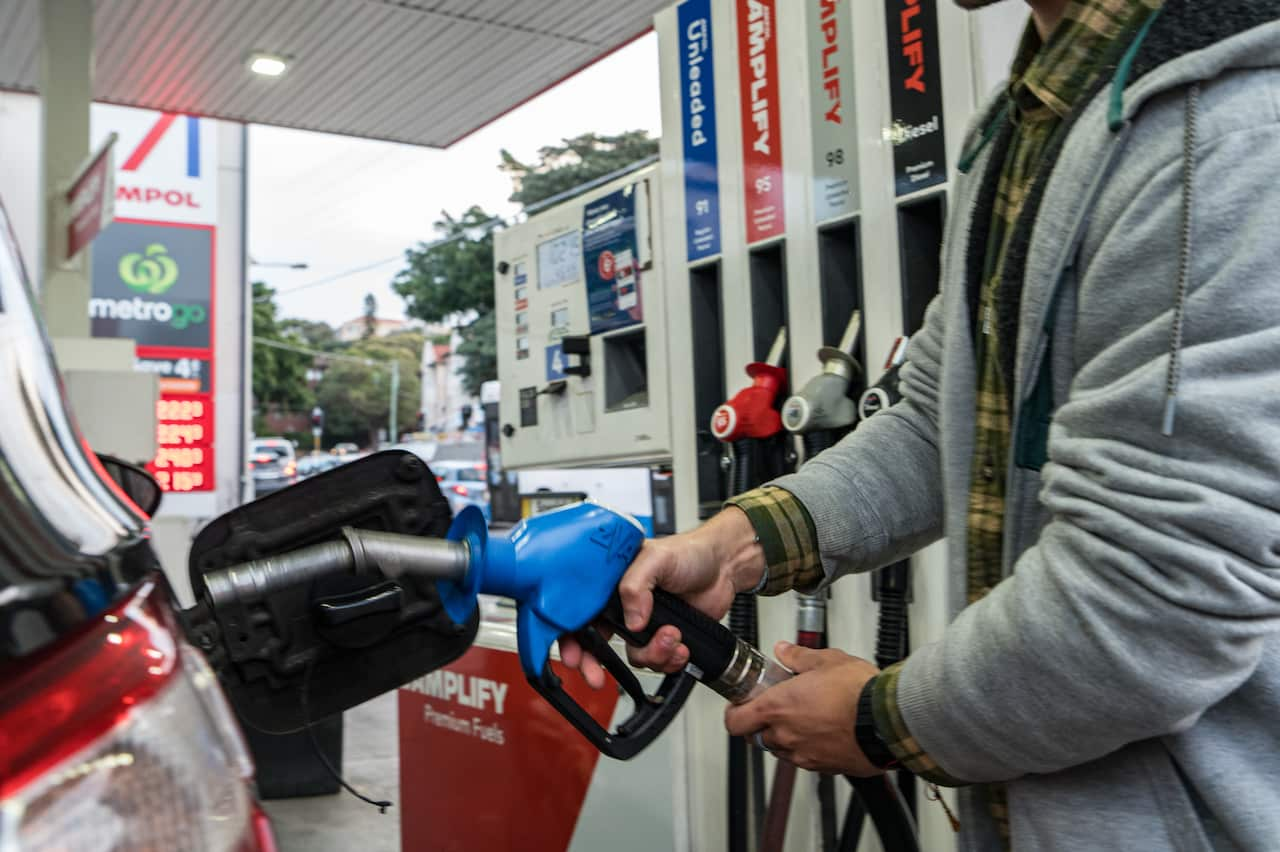 A person standing at a petrol bowser who is about to re-fuel their car.