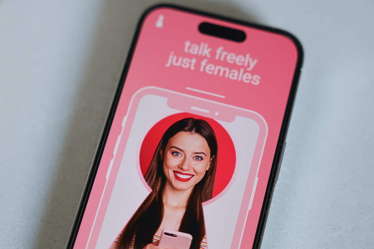 A smartphone with an app open that shows a photo of a smiling woman with the text "talk freely just females".