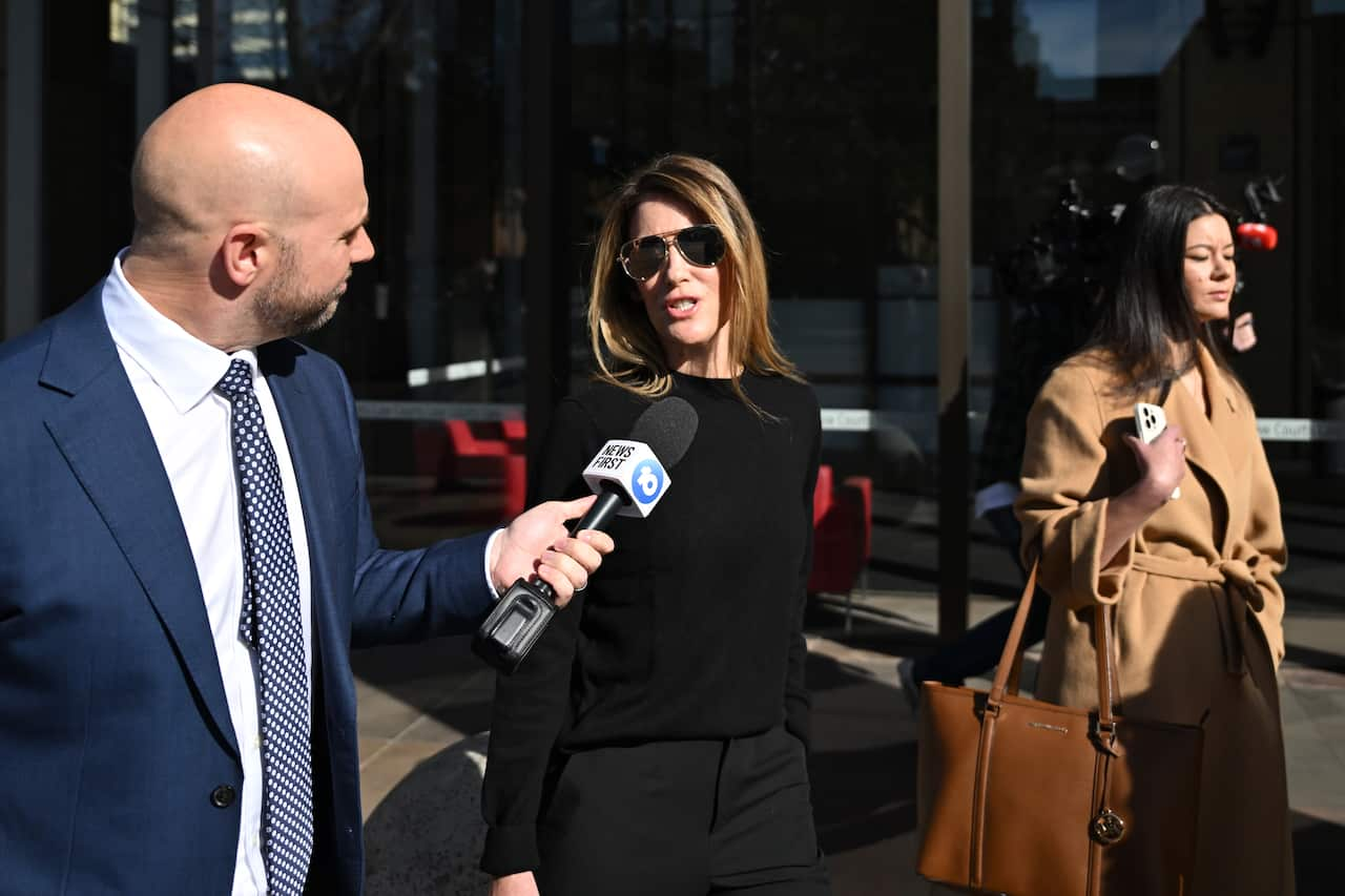 A woman speaking to a journalist as she walks outside.