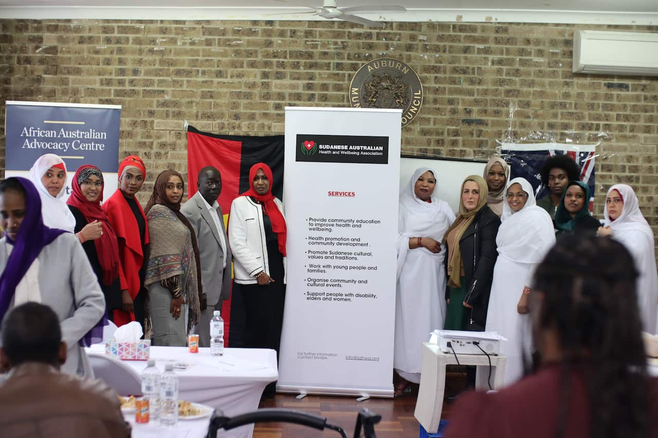 A group of women standing near a sign in a room