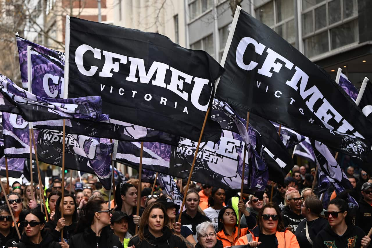 A large group of people holding up CFMEU banners and signs while marching through the street.