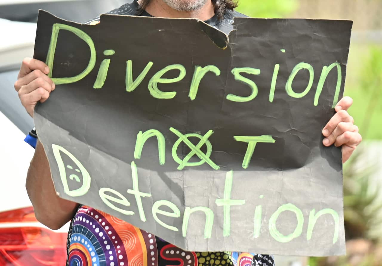 A man holding a protest sign against children being locked up outside the Don Dale Youth Detention Centre in Darwin.