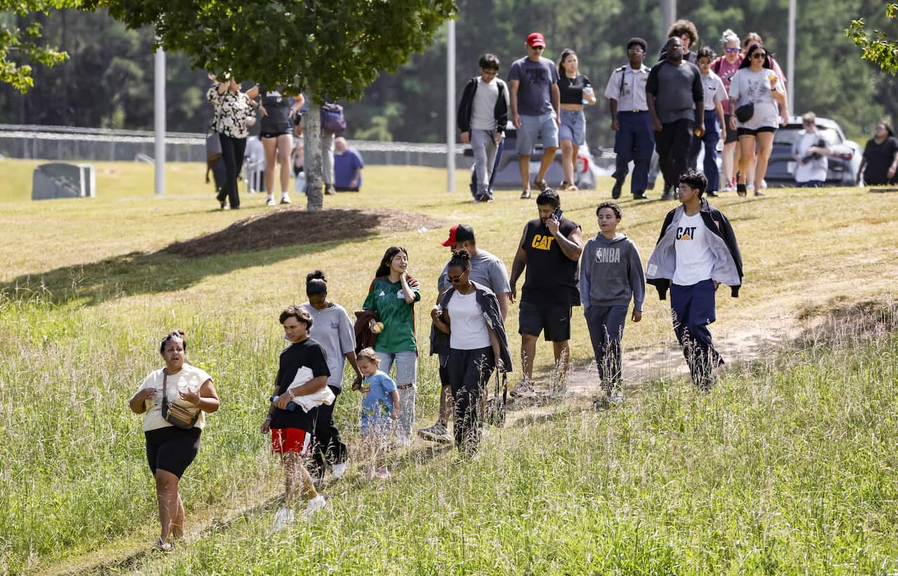 A group of people walk down a grass path. 