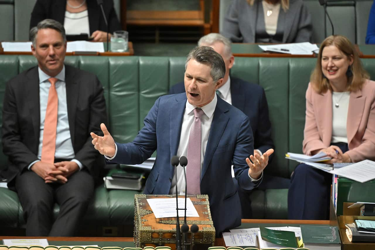 A man wearing a suit speaking at a podium. 