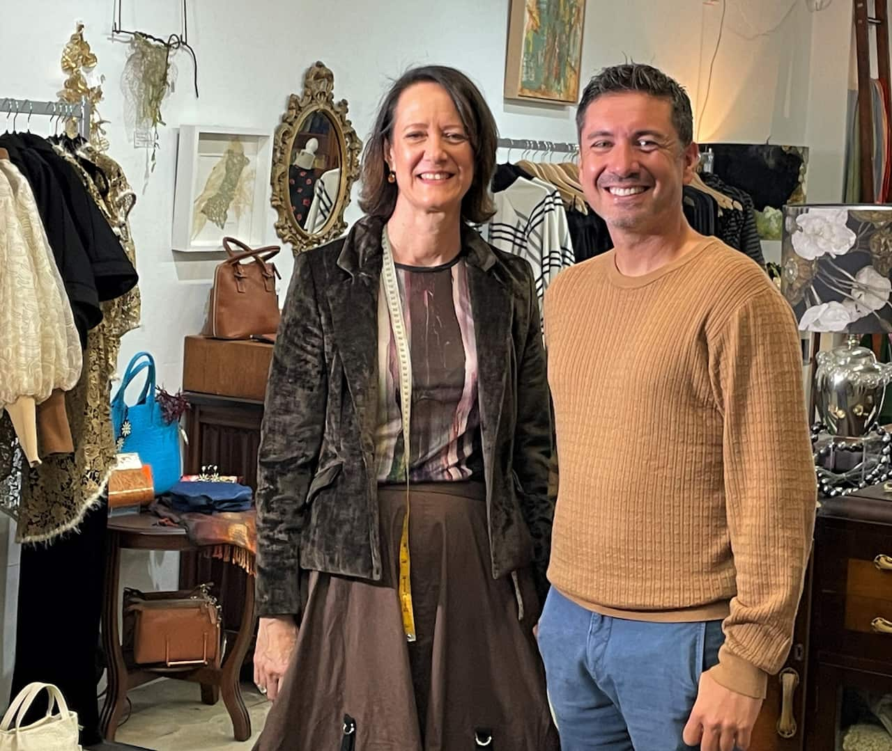 A woman in a brown jacket stands next to a man in an orange jumper in a store.