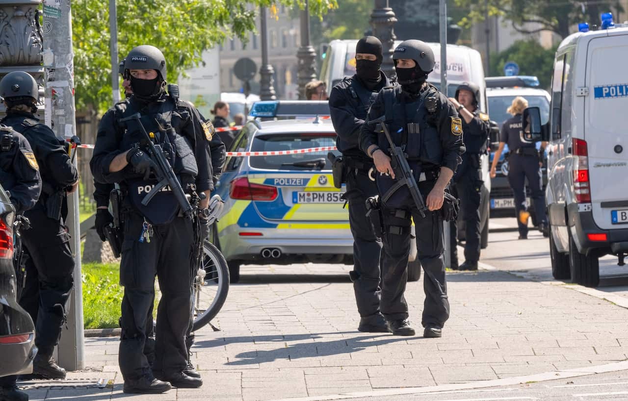 Several police in black uniforms holding rifles.