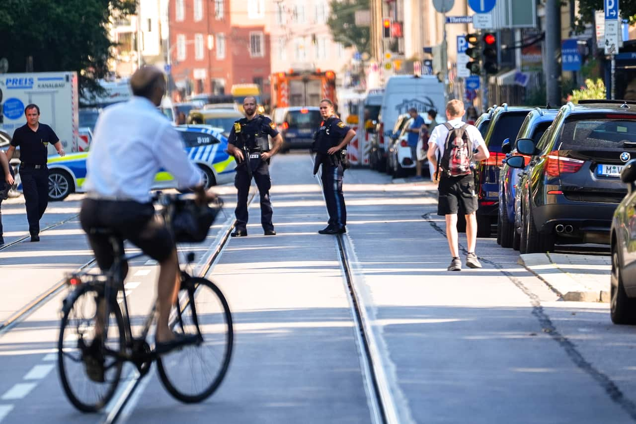 A person rides a bike on a ride as police stand nearby. There are cars parked alongside the road.