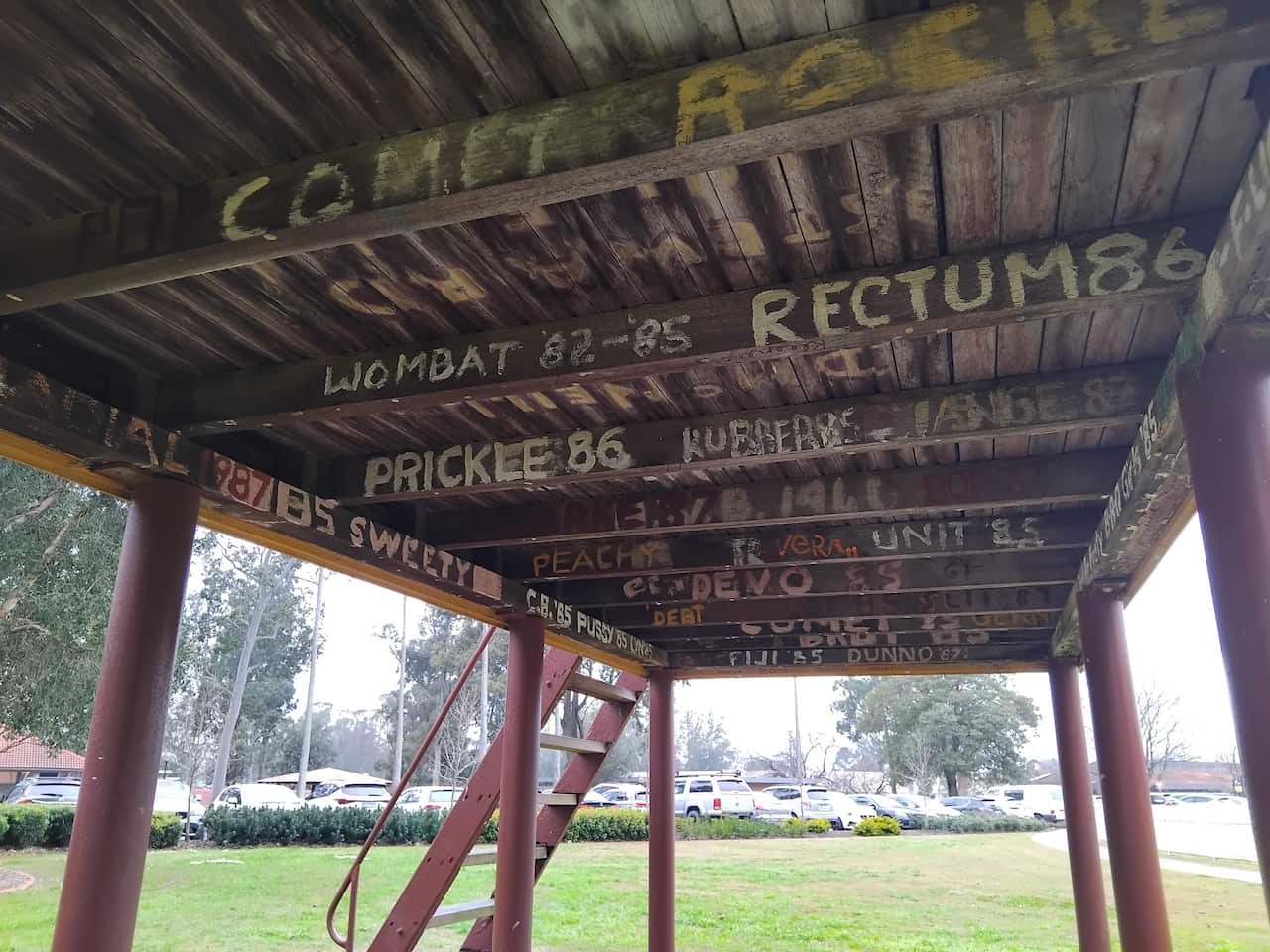 The underside of a wooden scoreboard, painted with dozens of nicknames