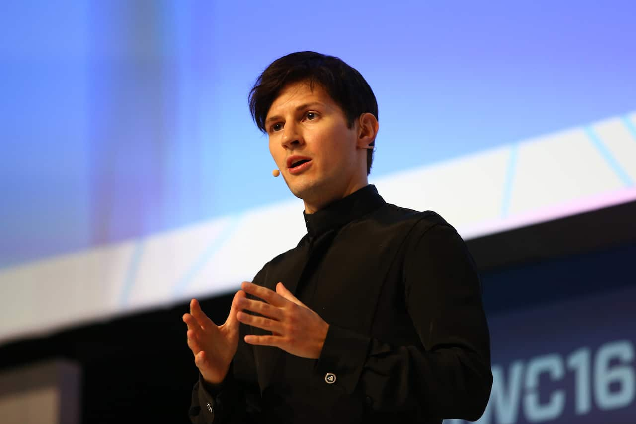 A man standing on a stage and speaking to an audience.