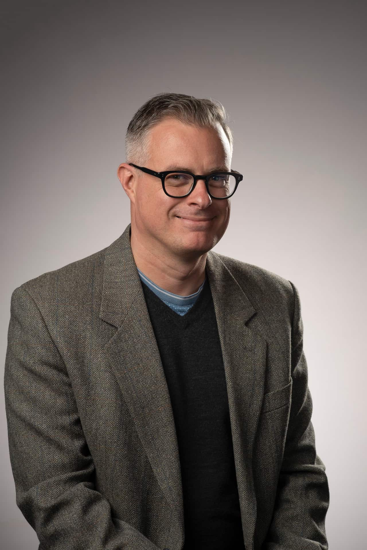 A man with glasses and a grey suit 